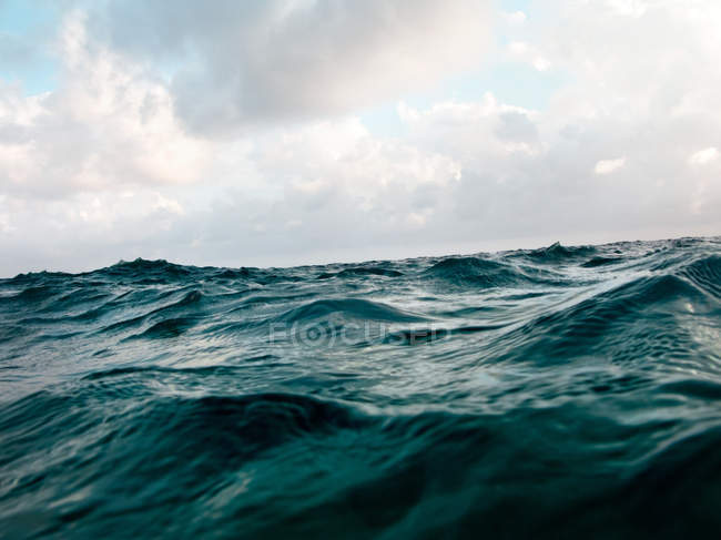 Océano ola superficie de agua con cielo nublado - foto de stock