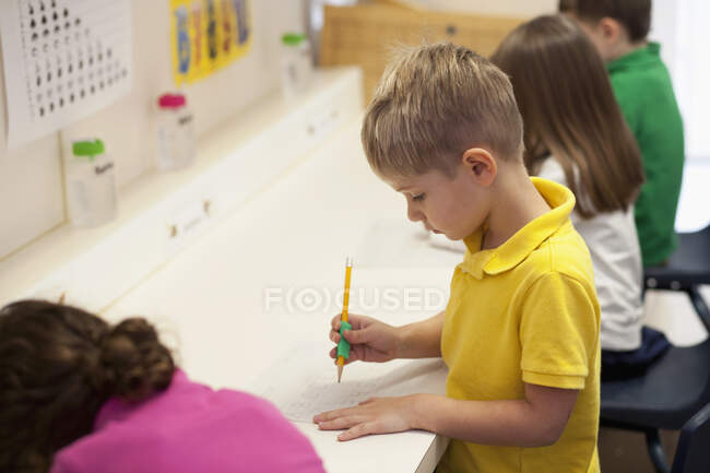 Crianças escrevendo em sala de aula — Fotografia de Stock