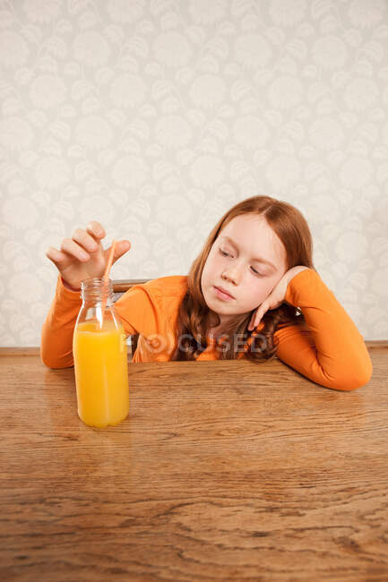 Chica mirando a la botella de jugo de naranja - foto de stock