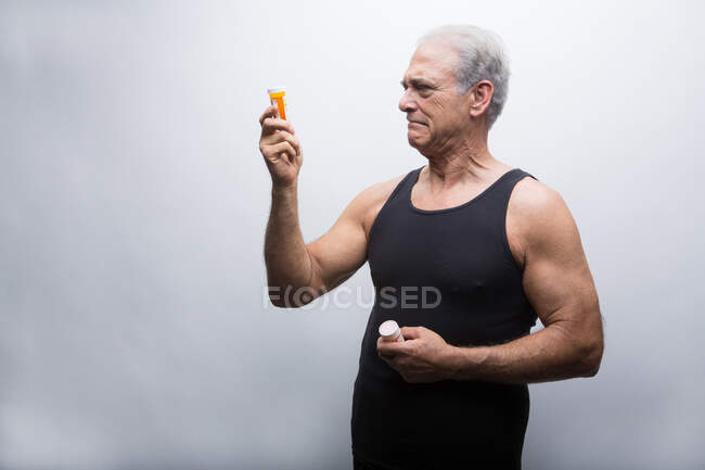 Homem sênior olhando para garrafas de pílula — Fotografia de Stock