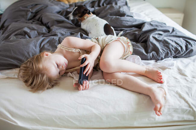 Menina deitada na cama usando smartphone — Fotografia de Stock