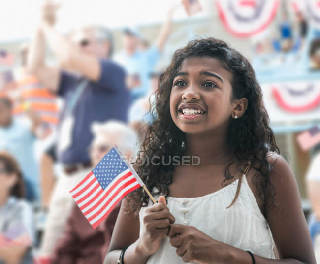Дівчина тримає американський прапор, виглядає тривожно — стокове фото