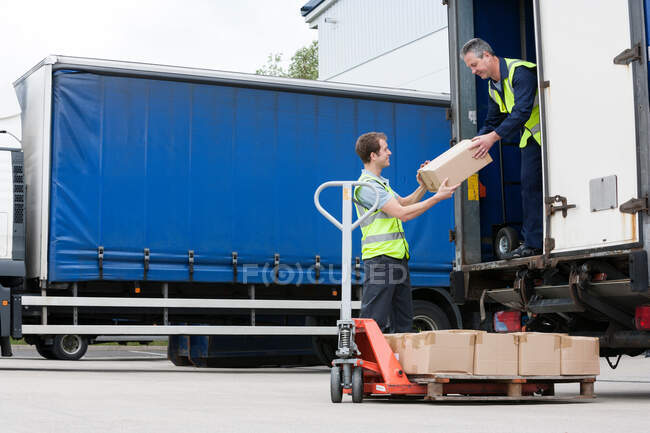 Два чоловіки розвантажують картонні коробки з вантажівки. — стокове фото