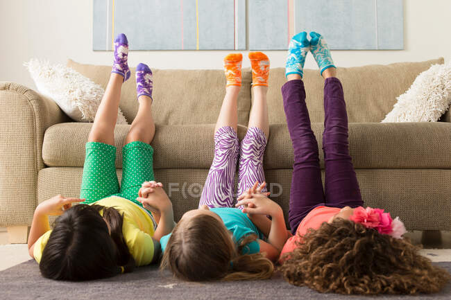 Три девушки лежат на полу с поднятыми ногами — стоковое фото