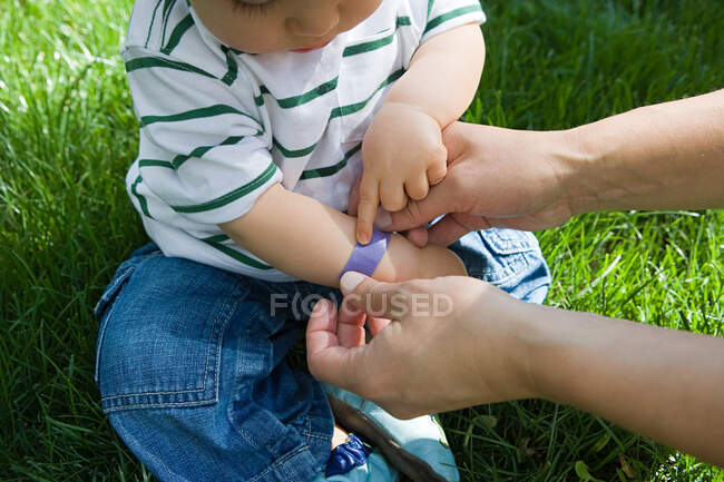 Adult putting plaster on baby boy — Stock Photo