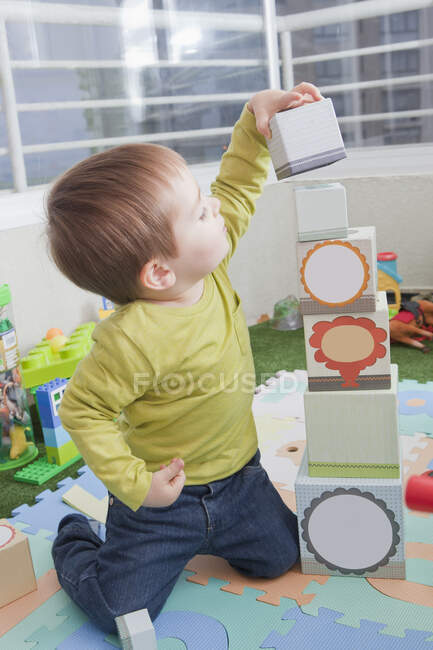 Menino empilhando blocos de jogo em casa — Fotografia de Stock