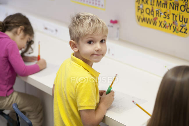 Niños pequeños escribiendo en el aula - foto de stock
