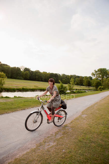 Mujer montando bicicleta en carretera rural - foto de stock