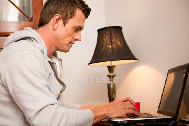 Uomo che utilizza un computer portatile a casa — Foto stock