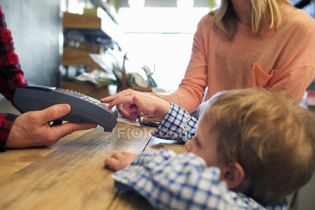 Niño usando la máquina de tarjeta de crédito en la tienda - foto de stock
