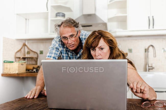 Älteres Paar benutzt Laptop in Küche — Stockfoto