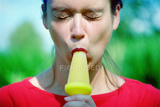 Mujer comiendo un caramelo de hielo - foto de stock