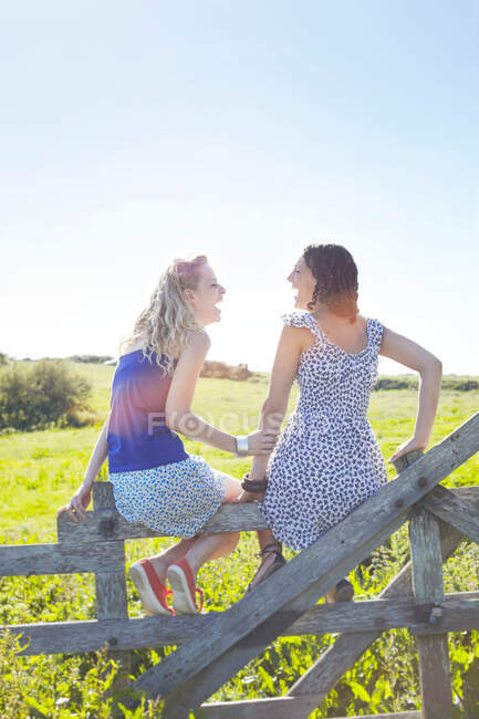 Two girls sitting on a fence — Stock Photo