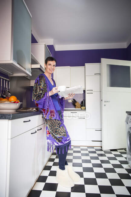 Frau liest Zeitung in Küche — Stockfoto