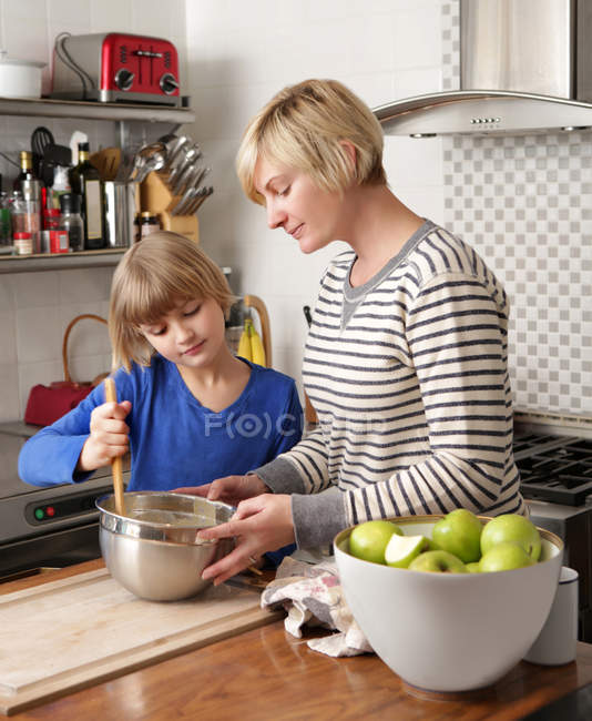 Madre e hija en cocina preparando comida - foto de stock