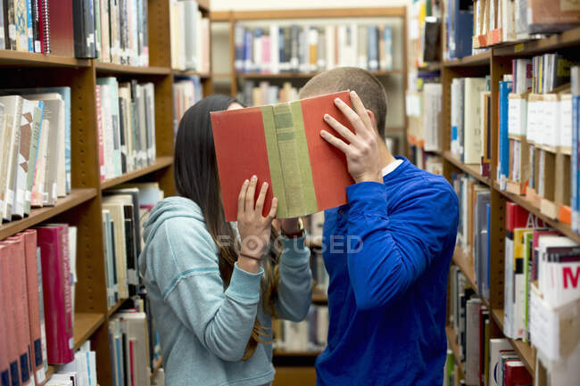 Молодая пара прячется за книгой — стоковое фото