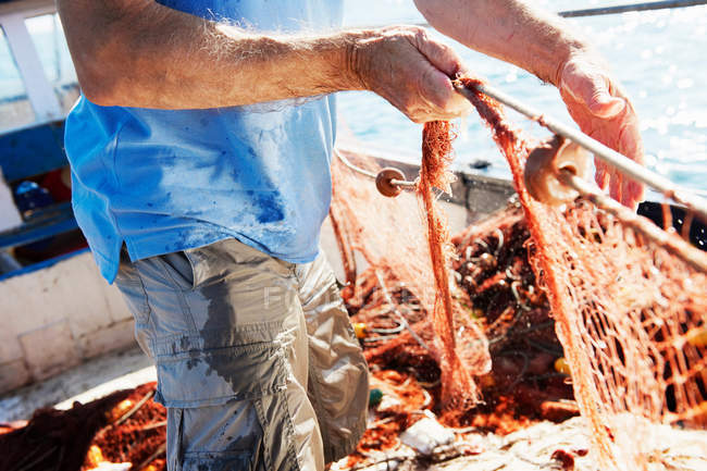 Обрезанный образ рыбака, затягивающего сети — стоковое фото