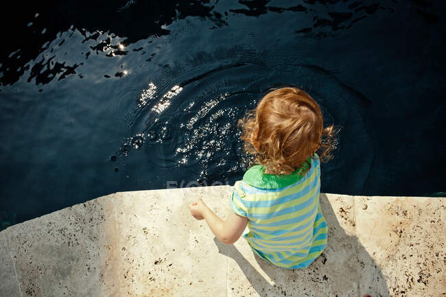 Fille assise au bord de la piscine — Photo de stock