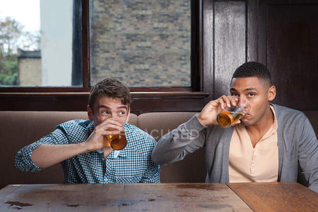 Молоді люди п'ють пиво в барі — стокове фото