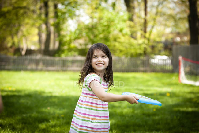 Молода дівчина, метання фрісбі в саду — стокове фото