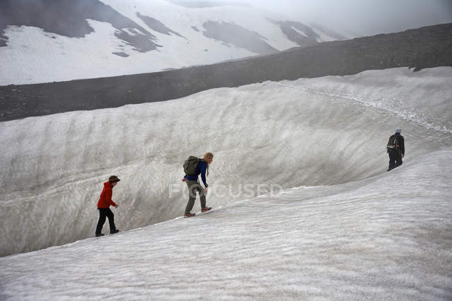 Family hiking on snowy hillside — Stock Photo