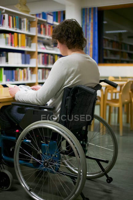 Homem com deficiência ler na biblioteca — Fotografia de Stock