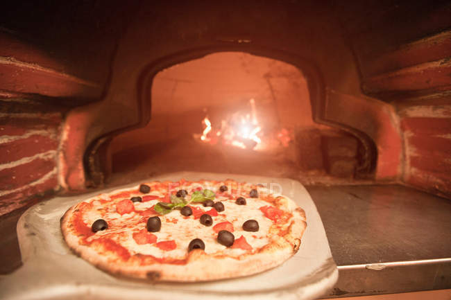 Koch zieht Pizza aus dem Ofen — Stockfoto