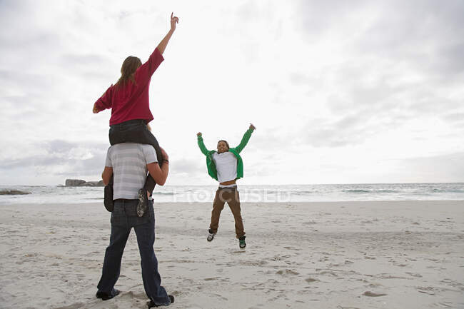 Молодой человек несет девушку на плечах на пляже — стоковое фото