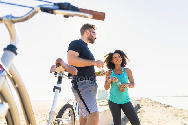 Pareja tomando un descanso del ciclismo, sosteniendo la bebida botella - foto de stock