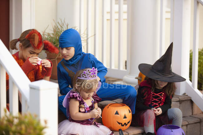 Children sitting on steps and enjoying treats — Stock Photo