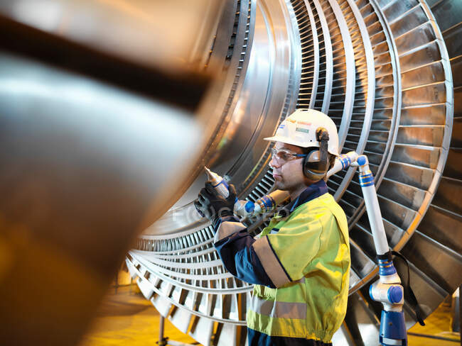 Un travailleur inspecte une turbine dans une centrale électrique — Photo de stock