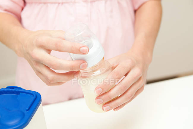Close up of mother preparing baby formula, cropped shot — Stock Photo
