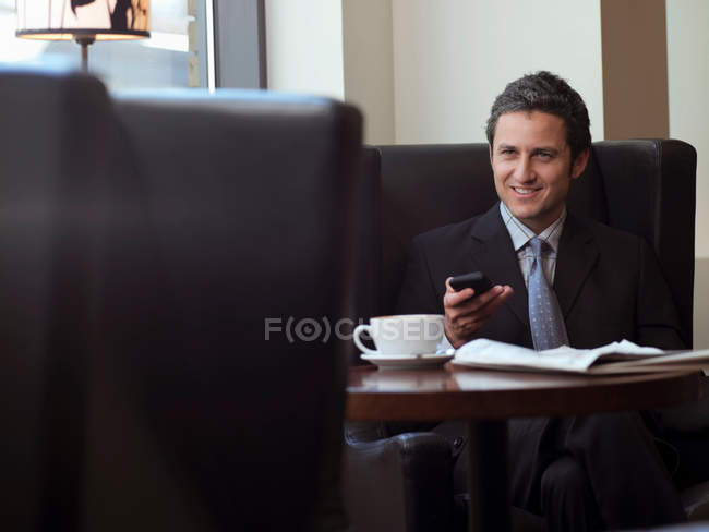 Uomo d'affari che utilizza il telefono cellulare in caffè — Foto stock