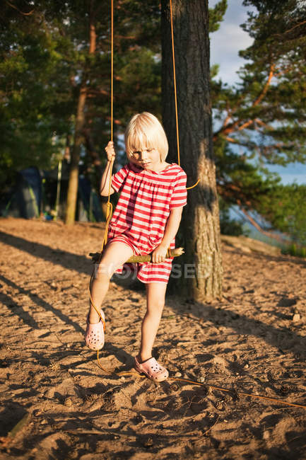 Дівчина грає на дереві, що гойдається в лісі — стокове фото