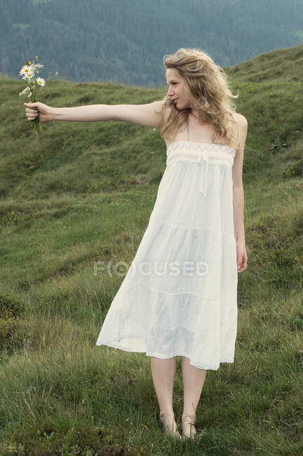 Femme portant des fleurs dans la prairie rurale — Photo de stock