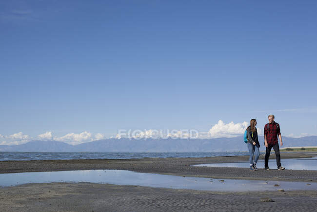 Молода пара йде, дивлячись один на одного, Велике Солоне озеро, Юта, США. — стокове фото
