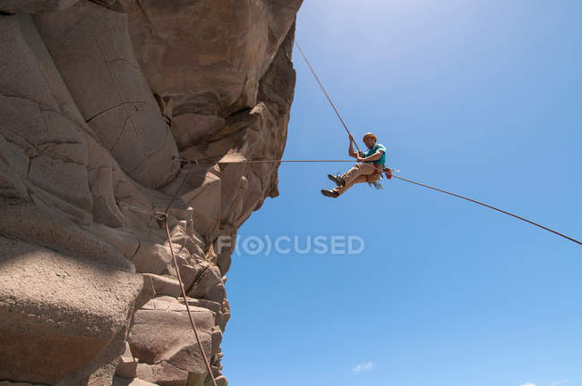 Rock climber abseiling jagged cliff — Stock Photo