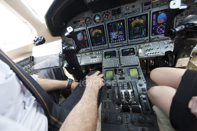Обрезанный кадр мужского и женского пилотов коленями в кабине частного самолета — стоковое фото