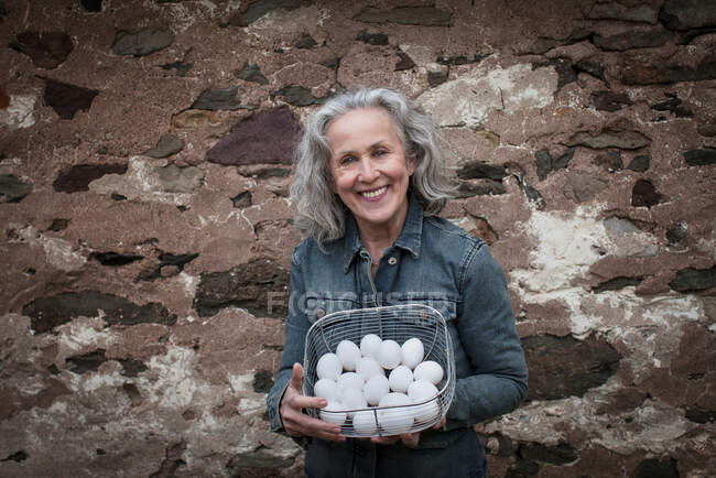 Seniorin mit Korb voller Eier — Stockfoto