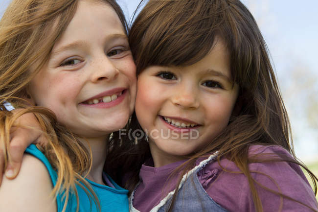 Улыбающиеся девушки, обнимающиеся на улице — стоковое фото