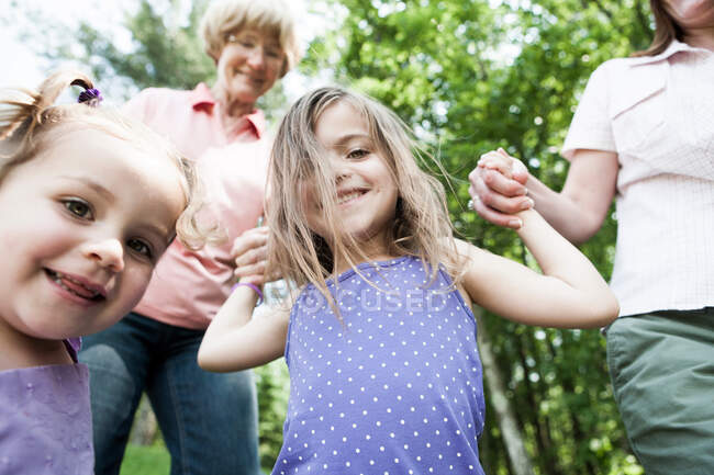 Familia de tres generaciones cogida de la mano, sincera - foto de stock