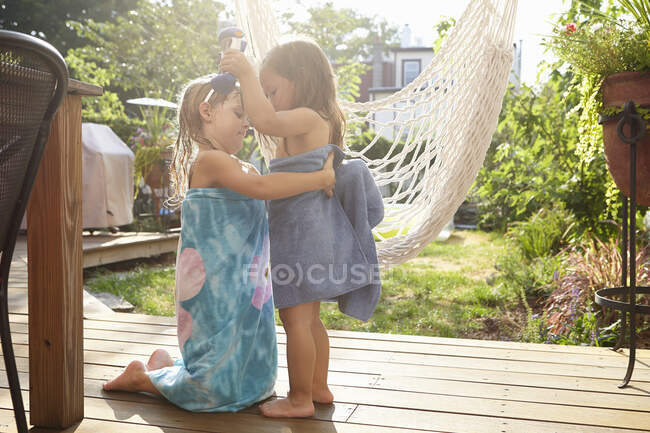 Girl wrapping friend in towel on porch — Stock Photo