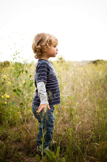Niño de pie en el campo - foto de stock