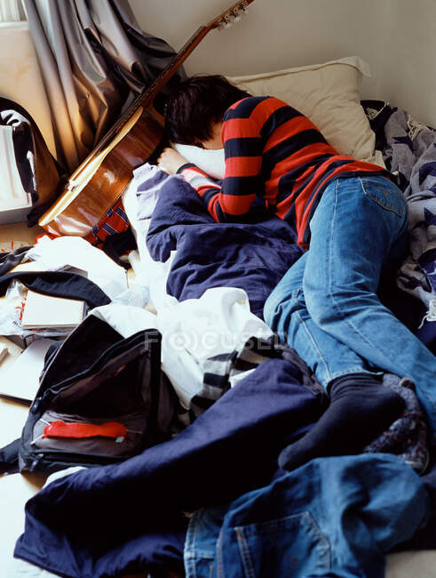 Junge schläft auf unordentlichem Bett — Stockfoto