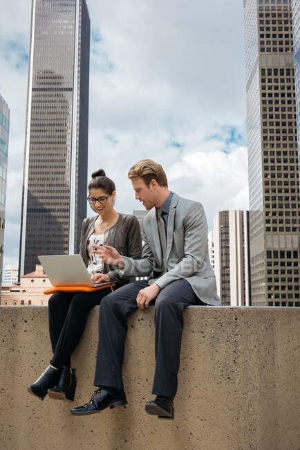 Homme d'affaires et femme utilisant un ordinateur portable sur le mur, Los Angeles, États-Unis — Photo de stock
