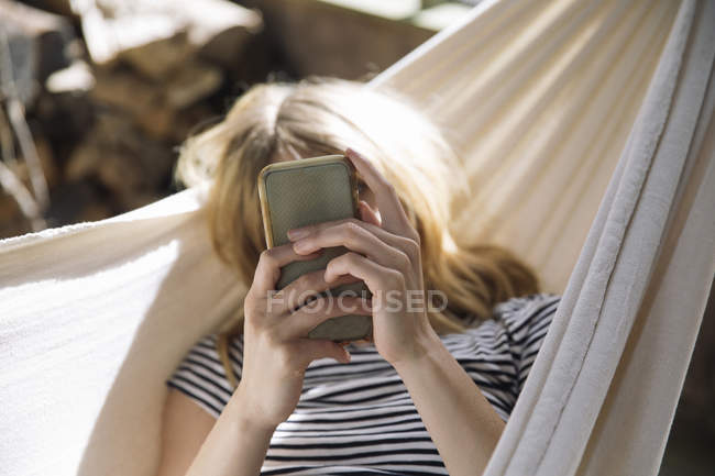 Frau benutzt Handy in Hängematte — Stockfoto