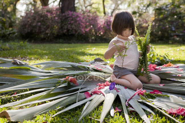Mädchen mit Farn sitzt auf Blume und Blatt im Garten — Stockfoto