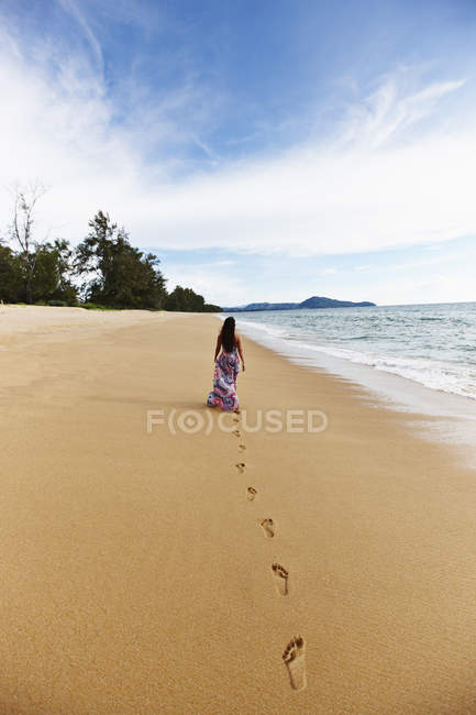 Woman making footprints on sandy beach — Stock Photo