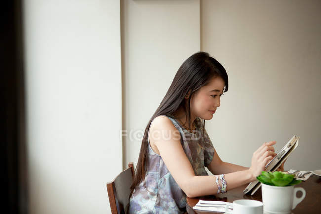 Молодая женщина использует цифровой планшет в ресторане — стоковое фото