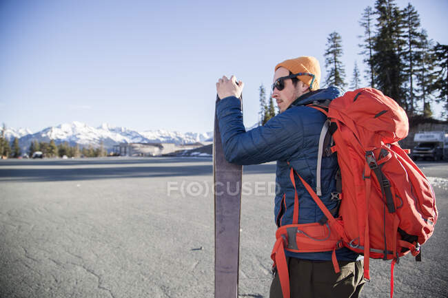 Young male skier in parking lot with distant snow capped Mount Baker, Washington, USA — Stock Photo